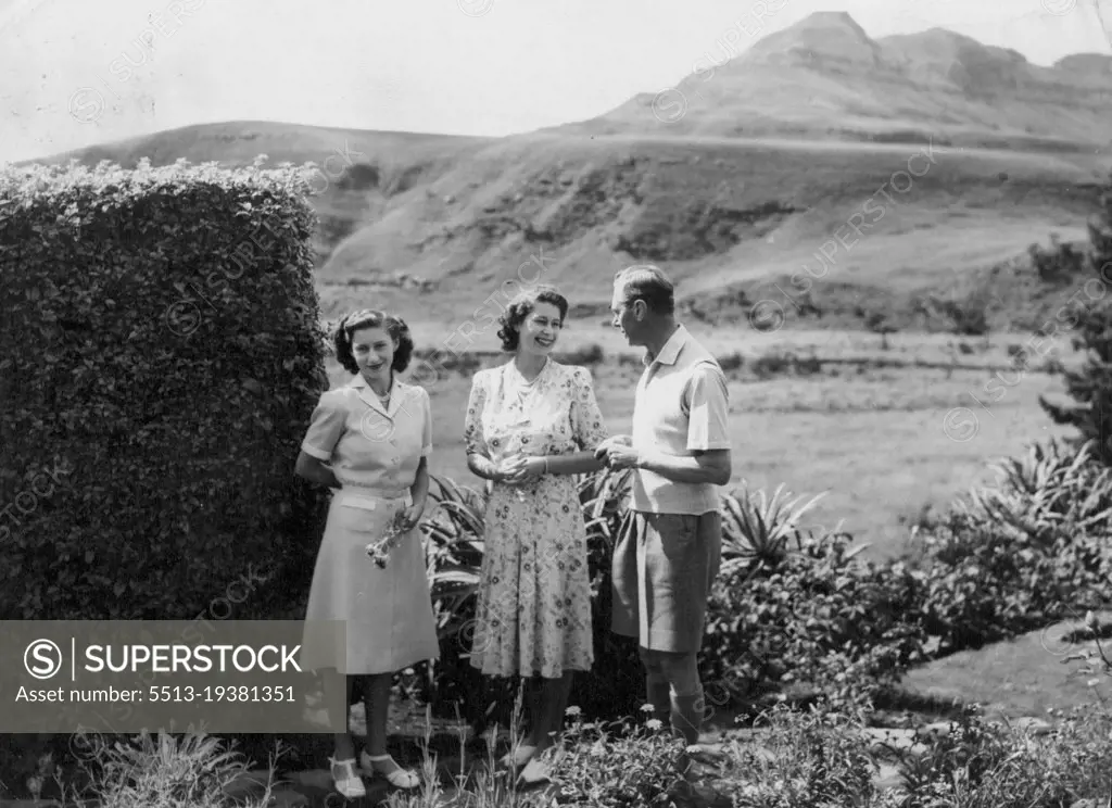 The King And His Daughters On Holiday In Natal -- Princess Elizabeth smiles at the King in the *****  spaces of the Natal national Park. On left, ***** a flower, is Princess Margaret.The Crowded South African tour of the British Royal family was interrupted for four days while King George, Queen Elizabeth and their daughters, Princess Elizabeth and Margaret took a well-earned rest in the Natal national park, situated on the Natal-Basutoland border 60 miles south-west of Ladysmith. The Royal Party stayed in a thatchod hostel at the foot of the Drakensburg Mountains, from where they were able to take walks in the Drakensburg foothills.The Princess were also able to do some swimming. March 22, 1947.