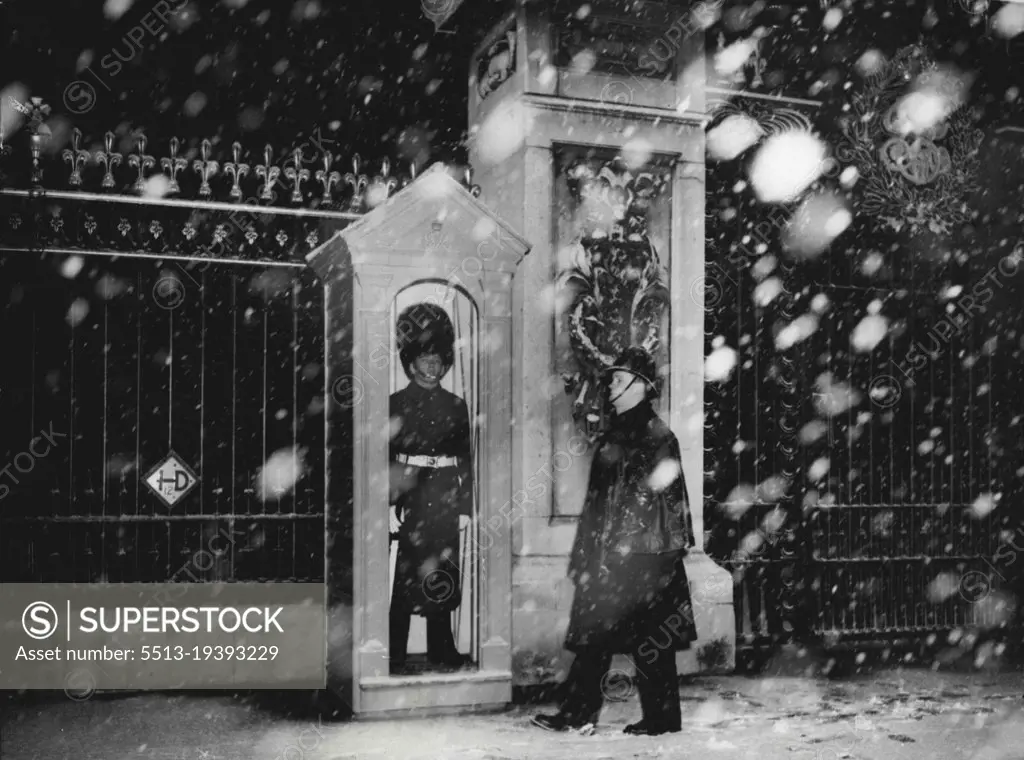 His Regiment Has Just Returned From Malaya - A policeman wales past the sentry in his box outside Buckingham Palace, today Dec 4th, at 3.30 p.m., during London's first heavy fall of snow.The guard is of the 2nd battalion coldstream guards, which has just returned from service in Malaya, and is now carrying out guard duty at the Palace. December 4, 1950. (Photo by Associated Press Photo).