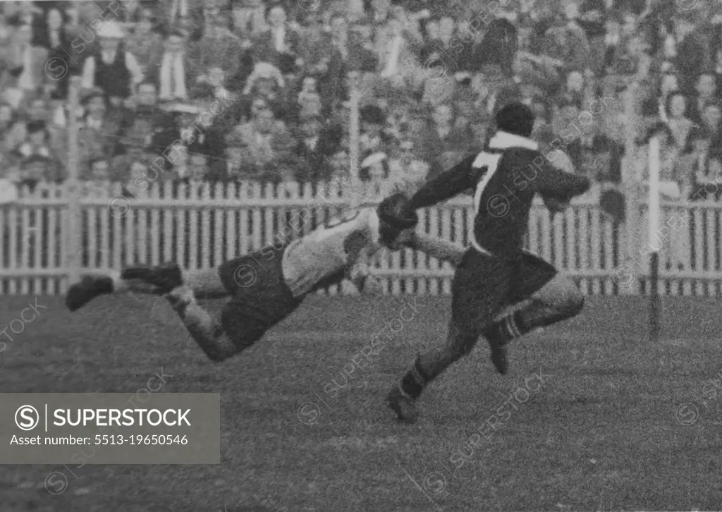 Powerful leg drive directs tackler's body to hit back of opponent's knees. Arms are outspread to trap his legs, pitch him to the ground. April 05, 1950.