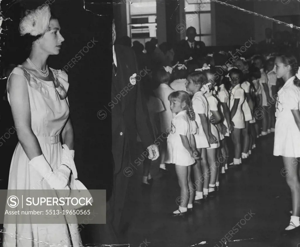 For her busy day today which included the investiture at Government House, a visit to Legacy House, Randwick and the surf carnival the Queen chose a dress of the utmost simplicity. The dress was sleeveless and had a frilled collar with bands which matched numerous tuckings on the skirt. The skirt was cut on slightly gathered lines. With it she wore a triple - strand necklet and white open-toed, sling-back shoes. Her tiny hat of matching yellow feathers was close-fitting and slightly side-swept. February 6, 1954.