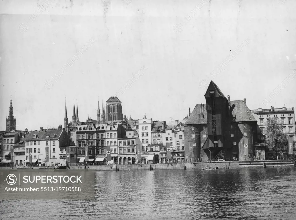 New Pictures of Danzig - Nazis Pour Into Free City.A new picture of the inner harbour of Danzig, known as the "Long Bridge". Also in the picture are three of Danzig's landmarks. Right foreground is the 15th century Krantor gate, notable for its stone and wood construction and now adorned with the Nazi swastika. Extreme left is seen the graceful spire of the Rathaus (City hall) and in centre the solid tower of the Marienkirche, one of the city's best-known churches. One thousand four hundred armed Germans and lorry loads of arms and munitions are reported to have arrived in Danzig from East Prussia. Rumours of an impending coup are circulating.More than 2,000 members of the German armed forces are now said to be in Danzig, and Polish military preparations are also reported. June 28, 1939.