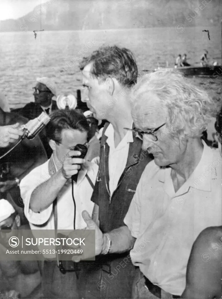 Piccard Dives 3,608 - Feet -- Professor Auguste Piccard (Right), gestures with his right arm as he talks into the Microphone after his descent, August 26th. His Son, Jacques (behind), is also speaking into the Microphone. Swiss-Born scientist Auguste Piccard, 69, One-time Stratosphere Balloonist, and his son Jacques, 37, plunged 3, 608 feet to the bottom of the mediterranean yesterday August 26th in his ten-ton steel "Bathyscafe." Piccard said afterwards that the diving craft could go to "Any Depths." He plans to make a three-mile dive in it at a point of Ponza and Sardina. September 07, 1955. (Photo by Associated Press Photo).