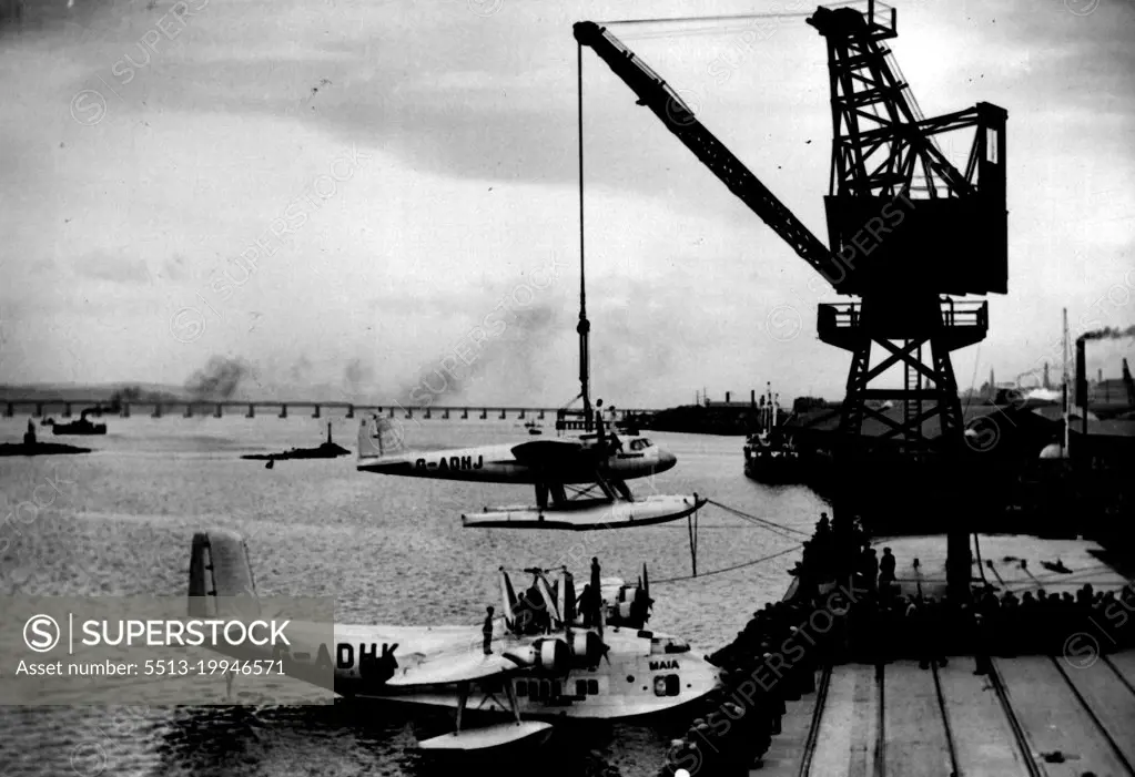 Pick-A-Back Plane Nearly Wrecked - Mercury being placed on the back of the parent craft, Maia, by crane in Dundee Harbour yesterday.Mercury, the upper component of the Short-Mayo composite aircraft, which is expected to start from the River Tay today on a non-stop flight to Capetown, came perilously near being wrecked in Dundee harbour yesterday. As the Mercury was being united to the parent craft, Maia, by a crane she was caught by a gust of wind and one wing swung very close to the crane before the mechanics hauling on ropes, regained control. September 23, 1938. (Photo by Topical Press).