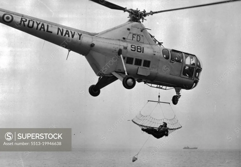 Trawling For Human Fish -- A general view of the scene over the Solent this afternoon as Wren 2nd/Officer Leta Ridley (Safety Equipment Officer) is hauled up to the helicopter after being "fished" from the sea during the demonstration of the new apparatus. At the R.N. Air Station Gosport (Hants) today, a demonstration was given of the new helicopter apparatus fro rescuing casualties form the sea, which has been developed by the Search and Rescue Unit at the R.N. Air Station, Ford, Sussex, The new apparatus is like a huge trawl net to "fish" survivors from the sea. January 24, 1955. (Photo by Fox Photos).