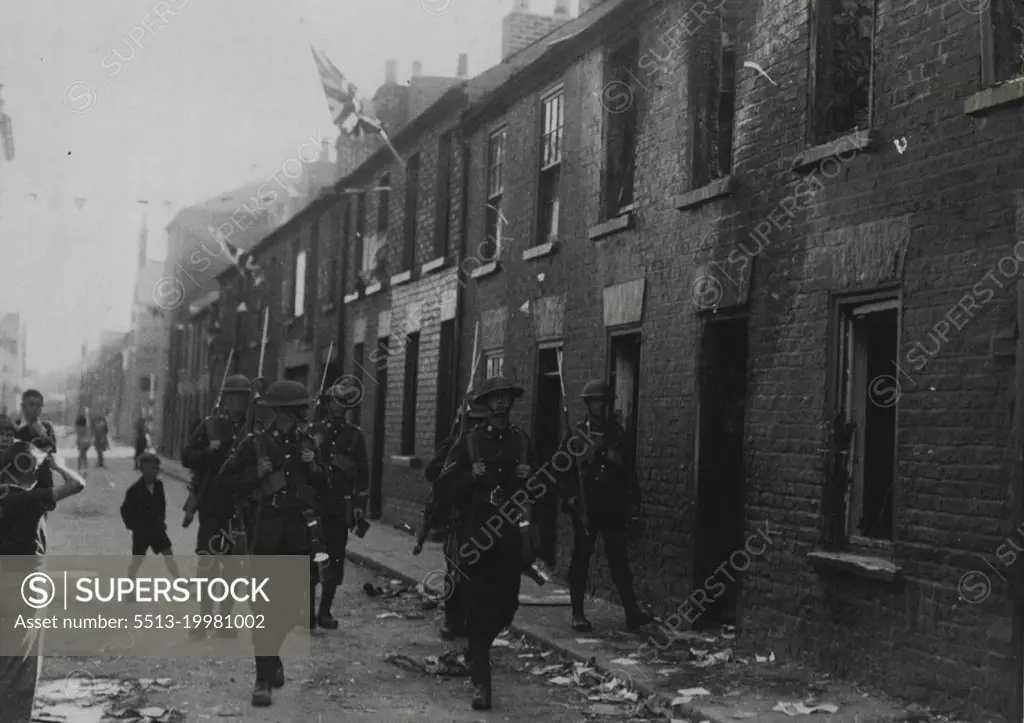 Serious Rioting in Belfast -- The scene of devastation in Little York Street, Belfast, following the rioting. Men of the Fighting Patrol of the Boarder Regiment are seen patrolling the street.Serious rioting broke out in the York Street Area of Belfast on Saturday, when a detachment of Orangemen, who were returning from Belfast's great "Twelfth of July" (Battle of the Boyne) demonstration, were fired on. Two persons were killed and many others wounded. July 16, 1935. (Photo by Topical Press).