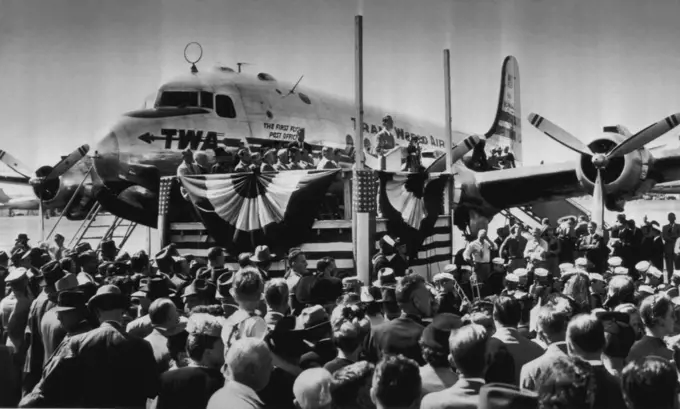 Hannegan Dedicates First Flying Post office - Postmaster General Robert E. Hannegan (speaking on platform, center) dedicates the nation's first flying post-office, a C-54 equipped to sort mail en route, during ceremony at national airport here today. The ship will make stops at Dayton, Chicago, Pittsburgh and New York on its initial flight, starting today. September 25, 1946. (Photo by AP Wirephoto).