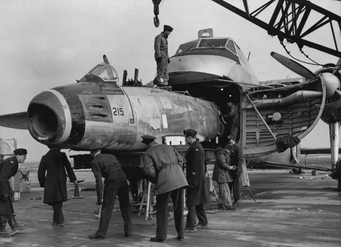 Bristol Freighter As Air Ambulance -- A damaged Sabre Jet (F-86 Sabre Jet) being placed inside the Bristol Freighter at Gros Tenquin, for its journey to England, to be repaired. Much in the same manner as a king-size reptile swallowing his food intact, this RCAF Bristol Freighter devours an F-86 Sabre jet at Gros Tenquin, near Metz in north east France, where the RCAF'S No. 2 Fighter Wing is stationed. As the comparatively little Sabre fuselage goes "down the hatch", supervising officers check i