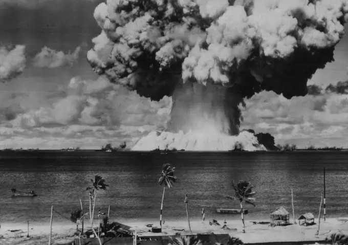 Second Bikini Blast As Viewed From Shore -- A column of water some 2,000 feet across at its base and 5,000 feet high boils up out of Bikini lagoon amid anchored ships as the underwater atomic explosion is set off on July 25. Bikini atoll shoreline in foreground. August 3, 1946. (Photo by AP Wirephoto).