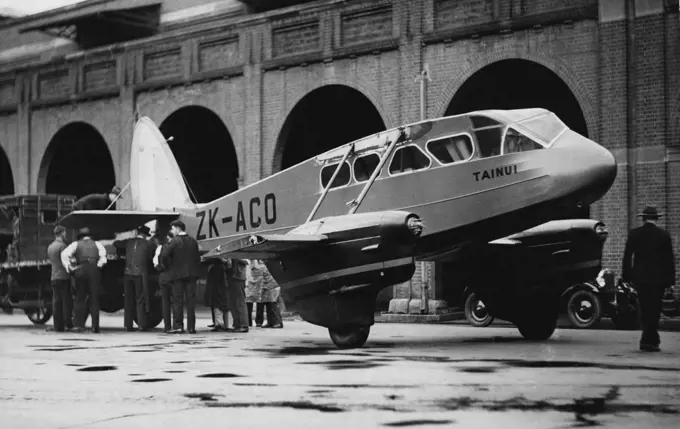 When Wings Weren't Wanted -- The big Dragon Rapide 'plane, Tainui, found its wheels more useful than its to-day. Its tail was fastened to a lorry outside a wharf at Daring Harbour, and it was towed through the streets to Mascot Aerodrome. The 'plane, which was used in the Centenary Air Race, arrived from New Zealand yesterday. It is here for the consideration of persons who may want to buy it. June 03, 1935.