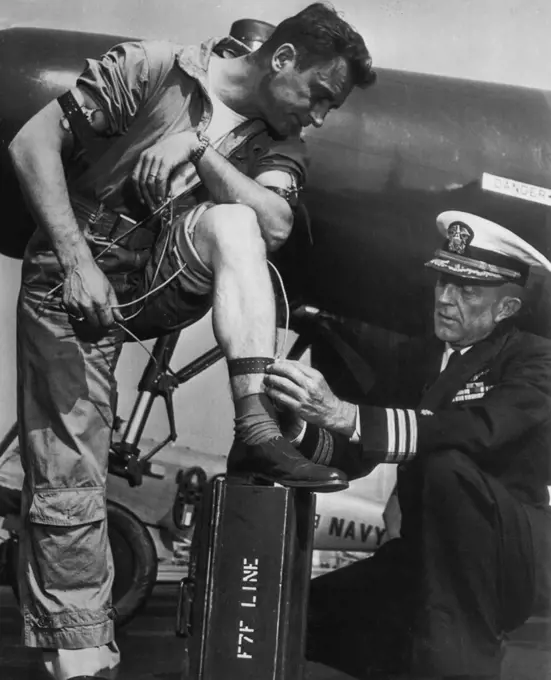 Wired For Sound Jet Flying -- Navy flight surgeon Comdr. Norman L. Barr attaches electodes to the body of pilot chief Joseph Kube during Navy's just completed series of successful tests and experiments for checking the minds and bodies of jet plane pilots while in flight. The electrodes register, through intricate radio devices, the heart and respiratory reactions during various stages of flight. The equipment was developed because of the number of air disasters caused by "pilot failure". Novemb