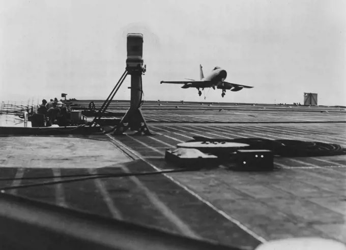 Trodi Checks Fury : Speed of a Navy North American XFJ-2 Fury Jet is checked by Trodi (padestal at left) as it lands on the USS Midway. The new instrument, a touchdown, rate of descent indicator, was developed and built by North American's Electro-Mechanical Department. It makes it possible to determine the proper rate of descent for carrier landing in a fraction of the time previously required. Trodi sends out two beams of light which the approaching plane intersects and the instrument then rec