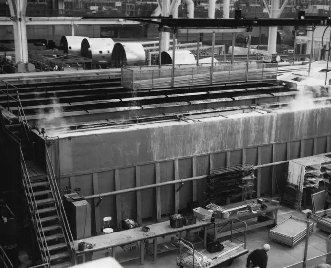 Airplanes En Masse -- Photo taken from overhead crane bay at Lockheed Aircraft Corporation's final assembly line in Burbank, Calif., shows big new transports and radar airplanes marching to completion in close ranks. Note comparative size of workman on floor below 50-foot horizontal stabilizer of the first transport and men on the tail of the second. Multimillion dollar array of airplanes above include big new Super-G transports for Eastern Air Lines and TWA (foreground) and early warning radar 