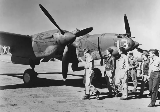 New U.S. Planes Arrive In Australia -- American fighter pilots inspect a newly arrived P-38 "Lightning", one of a large shipment of the U.S. fighter-interceptors which arrived recently in Australia. The P-38's, which had already seen service against the Axis in Europe and Africa, base their offensive strength on (1) high altitude performance, (2) speed in excess of 400 miles per hour and (3) strong firepower, including heavy machine guns and automatic cannon. February 22, 1943. (Photo by Interph