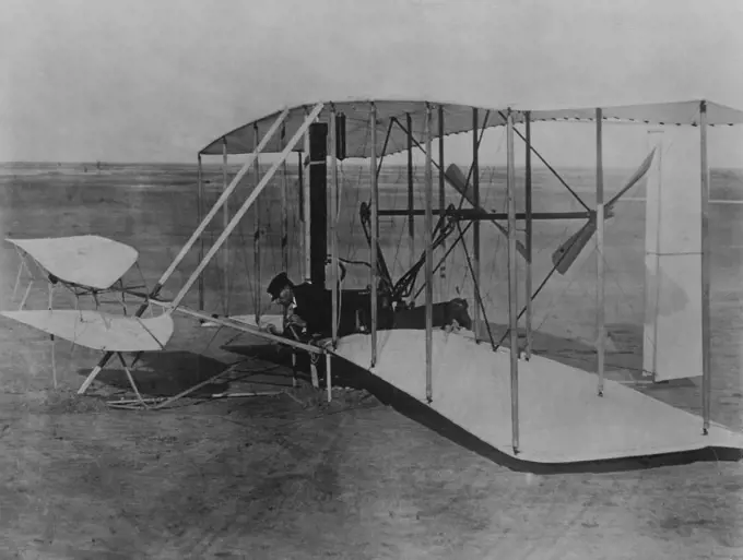 Wright Brothers 1903 Aeroplane (Kitty Hawk) on ground. Probably Wilbur Wright lying prone at controls. Evidence indicates photo was taken after first flight attempt, Kitty Hawk, N.C., 12/14/1903 with Wilbur piloting when aeroplane sustained minor damage shown to front elevator and supports. December 1, 1952. (Photo by Camera Clix).