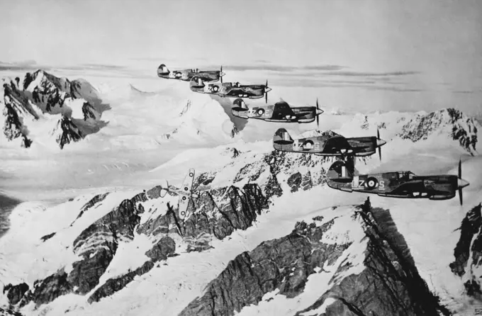 Canadian Airmen Cooperate with U.S. In Operations off American west Coast -- Kittyhawk fighter planes of the Royal Canadian Air Force wing in formation over an Alaskan mountain range in one of the patrol operations in which Canadian flyers are cooperating with United states airmen in operations in the North Pacific area. October 11, 1943.