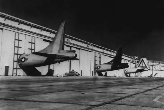 The Building's Big, But Not Big Enough - The tail structures of these early-modes B-36B air-planes are too big for the Consolidated Vultee aircraft plant here where they are being modernized into jet-augmented B-36D bombers. So the company cut circular holes in huge sliding doors for this porthole-like effect, while work proceeds on forward portions of the planes inside. October 13, 1950. (Photo by AP Wirephoto).