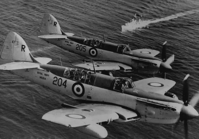 Combined Home And Mediterranean Fleet Exercises -- "Firefly" aircraft of the 14th. Carrier Air Group, carried on H.M.S. "Glory", flying in formation over Palmas Bay (Sardinia), and over British warships steaming in line ahead during the Combined Home and Mediterranean Fleet. Exercise which concluded with the arrival of the Fleets at Gibraltar on March 22nd. 1950. March 25, 1950. (Photo by Official Admiralty Photograph).