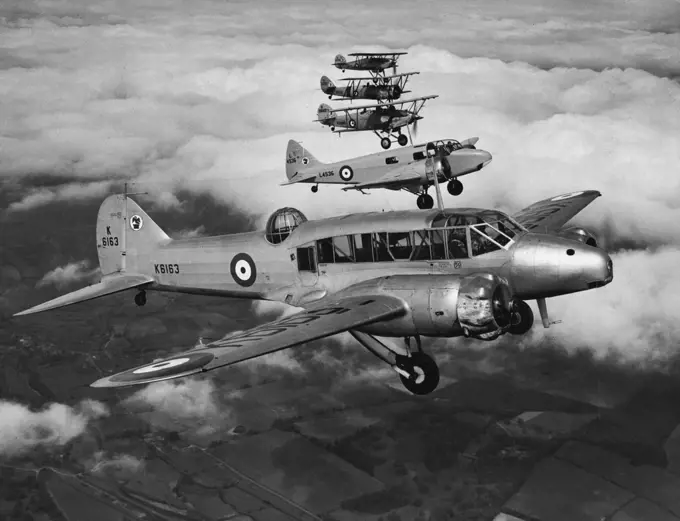 An Unusual Formation -- Formation flying of aircraft of widely different performances such as this is a difficult feat. These aircraft all belong to the central Flying School at Upavon. All the aeroplanes in this photograph are different. Reading from the camera they are the Avro "Anson" (coastal reconnaissance aircraft), "Oxford", twin-engined trainer, "Hart", bomber and training aircraft, Avro "Tutor" and "Fury," single-seater fighter. July 27, 1938. (Photo by Paul Popper).