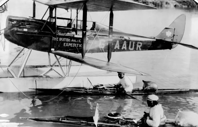 British Arctic Air Route Expedition: One of the Moth aeroplanes on floats, with two Eskimos in their Kayaks. December 28, 1931. (Photo by British Arctic Air Route Expedition Photograph).