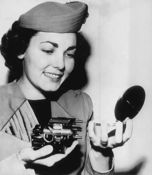 Tiny Motor Helps Fliers -- Jean Jettie, an airline hostess, compares a compact with a tiny hydraulic motor weighing less than a pound and developing 2½ horsepower during a demonstration here of robot gadgets designed to help pilots fly supersonic aircraft. The motor helps operate ailerons, rudders or elevators which otherwise could not be moved because of terrific wind pressures. It was perfected by the Minneapolis-Honeywell Regulator Co., and shown to the Airport Operators' Council convention h