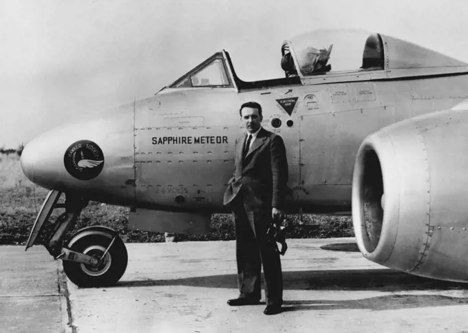 Collected Climbing Records. Wearing an ordinary lounge suit and regulation flying helmet, Flight- Lieutenant R.B. ("Tom") Prickett, 29-year-old test pilot is pictured before stepping into the plane behind him - the Hawker Siddeley Sapphire Meteor twin jet aircraft in which he collected four world records for Britain. Flying from the aerodrome here the aircraft climbed to 39,600 feet, or nearly seven and & half miles, in three minutes seven seconds. Other records scooped up by the Meteor were 9,8