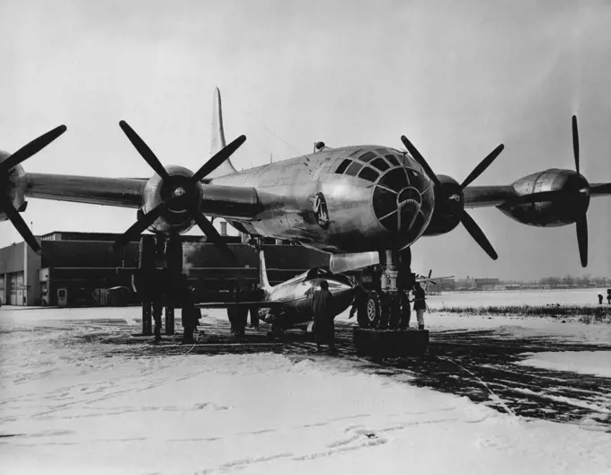 A new method of attaching experimental research aircraft to mother ships is shown here at Bell Aircraft Corp.'s Niagara Falls plant. The B-29 mother ship is raised on hydraulic hoists and, in this instance, the Bell X-1A is moved under the B-29 to be attached to the fuselage of the four-engine plane. Previous Bell X-1 airplanes were attached from a pit beneath the mother airplane. April 10, 1953. (Photo by Bell Aircraft Corporation).