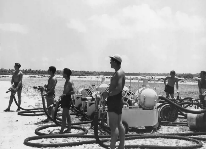 An Australian refuelling party at the edge of the airstrip on Cocos Island, waiting for a plane to land. October 12, 1953. (Photo by Qantas Photograph).