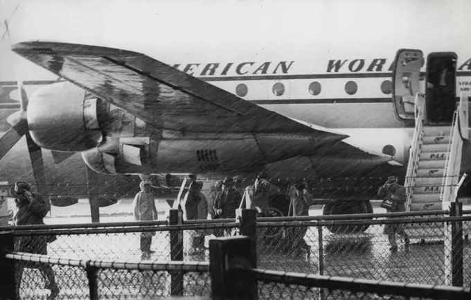 Passengers from A RAA Stratocruiser running thru the rain to the Customs shed at Mascot this afternoon. The plane had just arrived from the US. November 07, 1955. (Photo by Leyden).