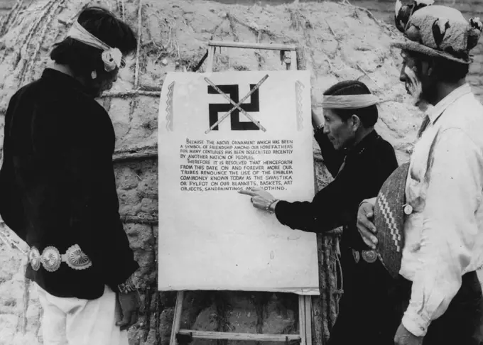 Arizona Indians Ban The Swastika Because of Nazi "Acts of Oppression" Indians Studying the Proclamation banning the use of the swastika displayed at a Ceremony at which blankets and clothing bearing the now unpopular symbol were burned. Left to right, Charley Turquoise (Navajo Indian), ***** (Apache Indian). Displeasure over Nazi "Acts of oppression" has led four Indian Tribes to Forswear the use of the Indian Swastika design on their blankets and baskets, in spite of the fact that the Indian S