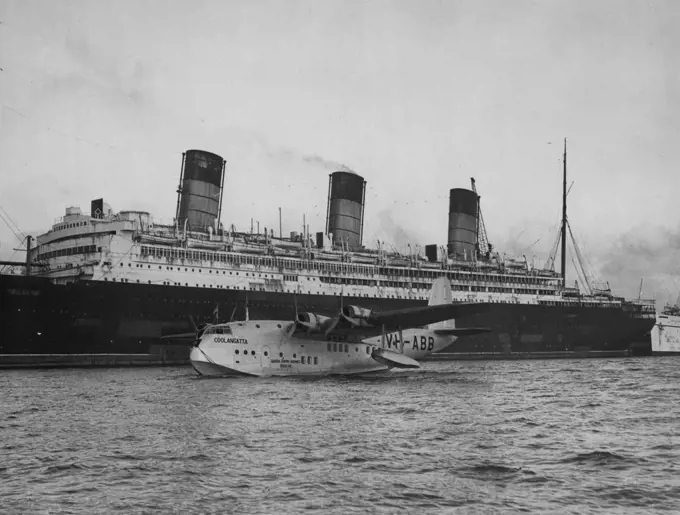 Arrival From Australia - Passes By Doomed Sea Giant -- Coolangatta, one of the fleet of Empire flying-boats, taxi-ing past the "doomed" liner Berengaria at No. 108 Berth in the New Docks at Southampton, at the end of her 12,000-,iles journey from Sydney. The Coolangatta was a day behind schedule when she was handed over by her Qantas Empire Airways' pilot to Captain I.G. Ross of Imperial Airways, at Singapore. The lost time was made up on the remainder of the journey, which was accomplished in f