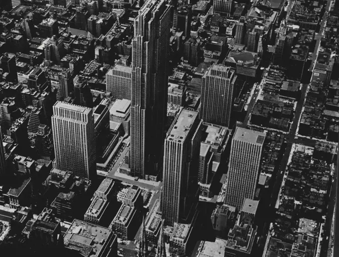 The Rockefeller Centre, New York -- This unique 15-building development in the centre of Manhattan occupies a little more than 12 acres between 48th and 51st Street and between Fifth Avenue and the Avenue of the Americas. The Esso Building, extreme right, forms the northern gateway to the Centre, with an entrance on 52nd. The building in the centre, of the picture, towering above all others, is the R.A.C. Building of 70 storeys. Right of it, and just behind the spires of St. Patrick's Cathedral, is the 41 -storey International Building. The 36-storey Time and Life Building stands at the extreme left of the photograph between 48th and 49th. July 28, 1954. (Photo by Camera Press). 