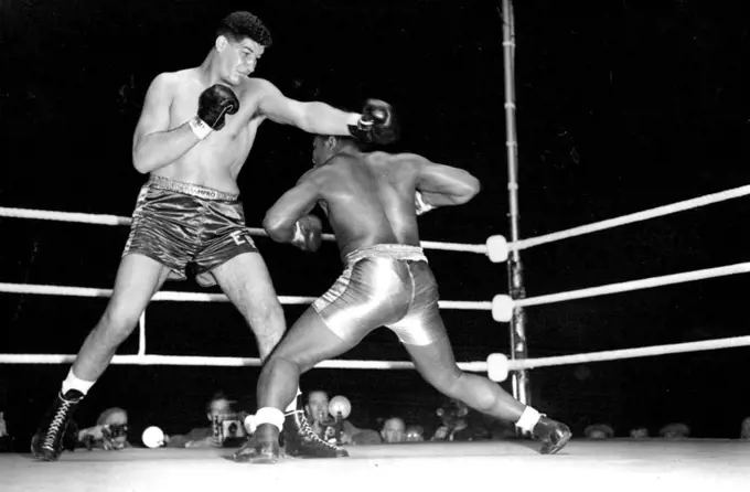 Giant South African boxer wins first fight in London. Templar slips under a straight left from his towering opponent. Ewart Potgieter the giant South African boxer defeated Simon Templar of Jamaica in their 8 round contest at the White City stadium, London. Templar - who could do little against his huge opponent - retired at the end of the 6th round after taking heavy ***** punishment. September 14, 1955. (Photo by Sport & General Press Agency, Limited).