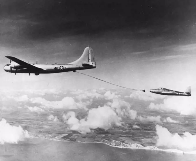 How Jets Refuel on Atlantic Flight -- A B-29 tanker plane with a fuel hose trailing out behind it is abut to make contact with an F-84 jet fighter in practicing the refueling operation being used on today's London-to-New York flight by two single-engine jets. Te jet plane here is one of the two making the flight. In the operation, the jet pilot rams a small boom extending from his wing into the funnel-shaped nozzle at the end of the tanker's hose. September 22, 1950. (Photo by AP Wirephoto).