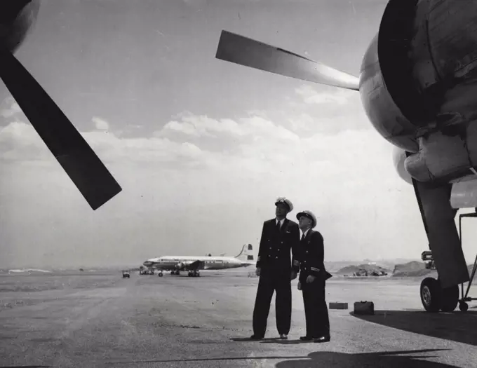 Out on the tarmac, Willcox and Captain E. Robertson (left) survey their aircraft before they take off on a flight overseas. April 20, 1955.