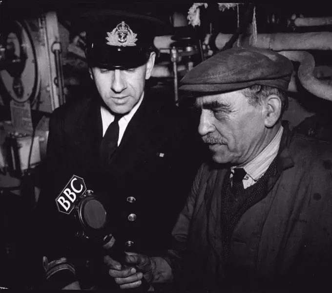 At a British port, the famous cruiser Shropshire, which took part in the bombardment of the Italian Red Sea ports, was handed over by the Royal Navy to the Royal Australian Navy as a gift from Britain to Australia, to replace H.M.A.A. Canberra, lost in action against the Japanese in the Solomons. A completer modern refit preceded the handling-over. Mr. Middleton, charge hand of the British fitters, gives the BBC a description of the work that has been done. With him in the engine-room is Lt. E. Heithersay, R.A.N., from Sydney, N.S.W. Recordings made at the time of the BBC visit were later broadcast in the BBC Overseas programmes "Calling Australia" and "Radio Newsreel". April 30, 1943. (Photo by BBC).