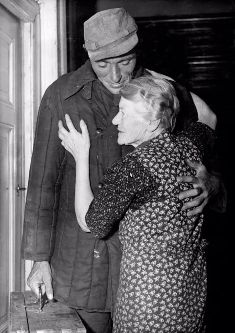 Welcome Home From Soviet Prison Camp. Kurt Mandelsdorff being greeted by his 79-year-old grandmother Anna Schulze after he knocked at the door for her West Berlin home. The returned wears a heavily padded Russian jacket and carries a wooden case he made in captivity for his return home. 34-year-old Kurt Mangelsdorff, former corporal if Hitler's armed ***** returned home to West Berlin September 26, after spending almost nine years of his life behind barbed wire in Soviet Russia. October 6, 1953. (Photo by Associated Press Photo).