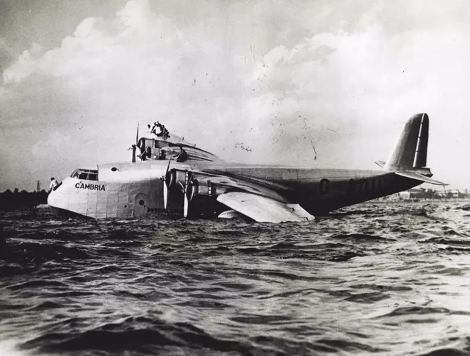 Imperial Airways Ship Crashes At Toronto - Members of the crew on the wing as the boat drifted to a stop. The Imperial Airways flying boat Cambria, which has successfully crossed the Atlantic Ocean three times, crashed in her landing at Toronto, Canada, September 3rd, when the gaint craft hit a floating landing, tearing a hole in one pontoon. The crew immediately took positions on the right wing, to counterbalance the damaged pontoon and save the craft from more serious disaster. September 5, 1937. (Photo by ACME).