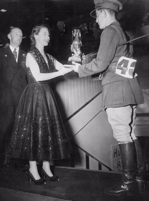 So The Cup Changes Hands - Princess Elizabeth, in a dark spiral-embroided evening dress presents the George V Gold Challenge Cup to Capt. K. Barry of the Eire Army, at the International Horse Show, at the White city, London last night. Captain Barry on his chestnut mare Ballyneety, had the only clear round in the finals. Lt. Col. Harry Llewellyn, Winner in 1948 and last year, came to grief on a white wicket gate which proved the "graveyard" of many hopes during the evening. Lt. Col. Harry Llewellyn was riding Foxhunter. July 26, 1951. (Photo by Paul Popper).