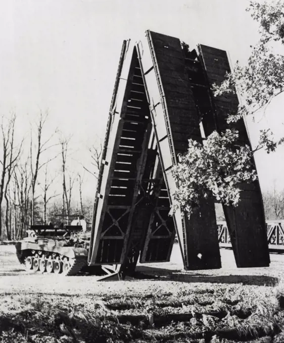 Bridging A Gap -- An experimental scissors-type bridge which is carried and launched by a turret-less tank, left, unfolds during a demonstration at Fort Belvoir, Va. Made of aluminum, the bridge is designed to carry loads up to 60 tons. Operated hydraulically, the bridge folds back over the tank for carrying. It was developed by the army engineers at their Fort Belvoir research Laboratories. December 29, 1953. (Photo by AP Wirephoto).