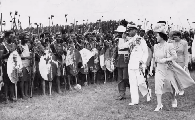 Their Majesties Inspected ***** Warriors -- The King salutes as Their Majesties, accompanied by the Paramount Chief Sobhuza Dlamini II, inspected some of the 4,000 Swazi warrior who assembled March 25. The Paramount Chief was arrayed in the height of the military fashion of the second empire, in an Azure tunic, scarlet trousers, gold epaulettes and a yellow diagonal sash.During his tour of South Africa the late King met these Swazi warriors in full war dress. The late King is accompanied by Queen Elizabeth and the new Queen. July 23, 1947.