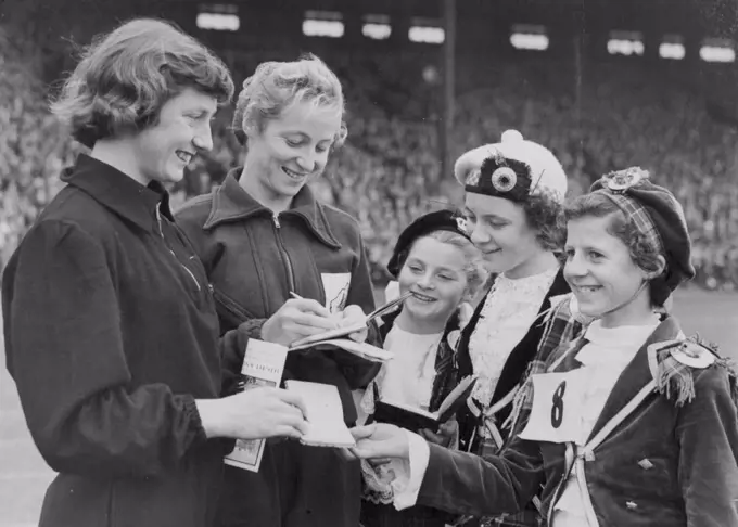 Olympic Stars Sign Up -- These little Highland dancers claimed autographs from Olympic Gold Medalists Yvette Williams of New Zealand (long jump), at left, and Australian Shirley Strickland (80 metres hurdles), during the annual City of Edinburgh Highland Games, staged at Murrayfield Rugby Ground. August 25, 1952.