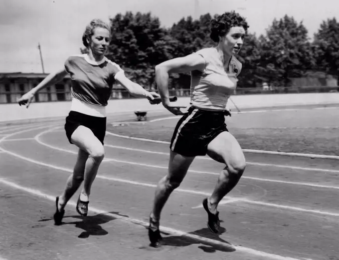 Olympic Girls From 'Down Under' Train At Paddington -- Australian sprinter and hurdler Shirley Strickland hands over to fellow-country woman Verna Johnston as they practice relay changeovers during a training spell with other Australian Olympic Games women athletes at Paddington Recreation Ground. June 19, 1952. 