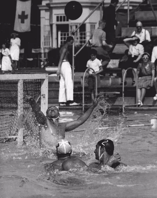 Olympics - Water Polo - Italy Beats Australia : P. Buonocore, Italian Goalkeeper in the Olympic water Polo Team, makes a save during attack by Australia in their match at the open air pool, Finchley, London, today July 30. Australian attacker (White cap) is Jack Ferguson. Italian Defender (Dark Cap No. 2) is N. Bulgarelli. Italy won 9-0. July 30, 1948. (Photo by Olympic Photo Association).