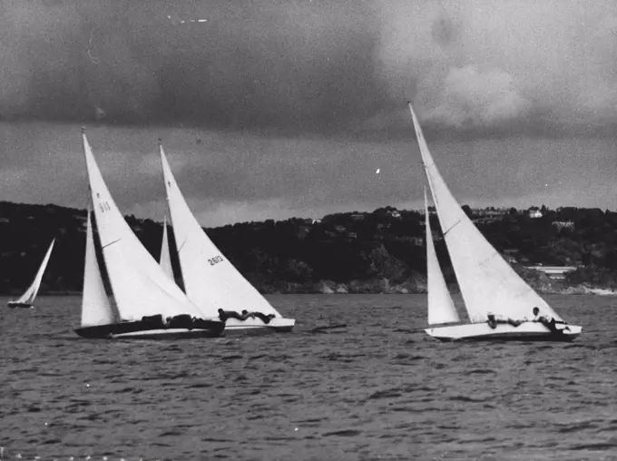 Keen Keelers In Olympic Yachting : Keen Olympic Yachting in the Star Class is seen at Torbay August 11 as crewmen flatten themselves against the decks of their craft to lessen the wind resistance. At left extreme rivalry as two South American entrants strain for the lead. No. 1911 (Nearest Camera) is Argentina's "Acturus" with helmsman J. Piacentini. No. 2613 is Brazil's "Buscape 11" with Helmsman J. J. Bracony. Yacht at right is unidentified. August 12, 1948. (Photo by Olympic Photo Association).