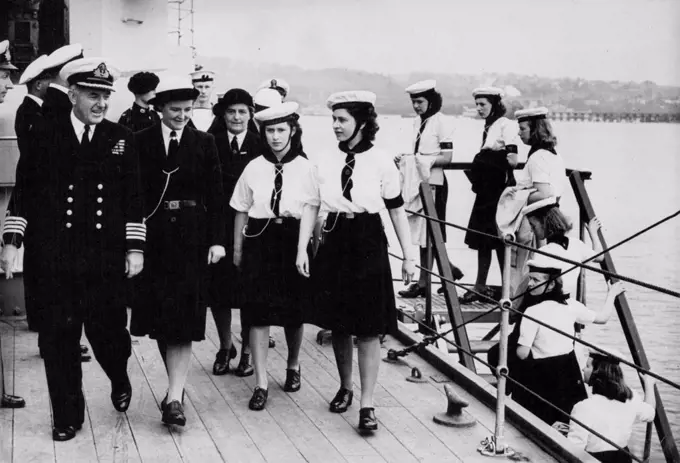 The Princesses Come Aboard : The Princesses, followed by Windsor Sea Rangers of the crew of M.T.B. 630, escorted by Captain Nicholl on the quarter-deck of H.M.S. Duke of York at Devonport yesterday (Wednesday). Princess Elizabeth and Princess Margaret, who are spending a few days aboard the Sea Rangers' training ship M.T.B. 630 in the River Dart, Devon, went with the ship's company by bus to Devonport, where they were entertained by Captain A. Nicholl, R.N. on board the battleship H.M.S. Duke of York for lunch and tea. July 25, 1946.