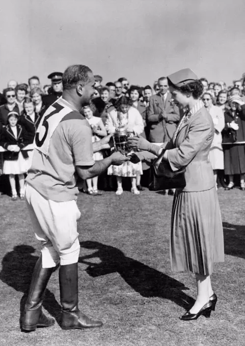 Royal Family see finals of Windsor Polo week. H. M. The Queen seen presenting the Royal Windsor Cup to Rao Rajah Ranut Singh, whose team Ratanada beat Ham in the final this afternoon. At Windsor today, the final matches of the Household Brigade Ascot Week Polo Tournament were played. Members of the Royal Family, who have been enthusiastic spectators at the matches throughout the week, were again watching today and the Royal Party included King Hussein and Queen Dina of Jordan who are visiting this country. June 18, 1955. (Photo by Fox Photos).