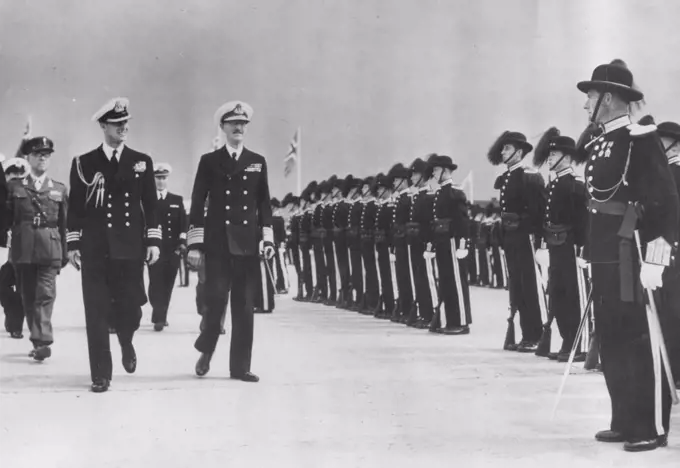 Duke And King Haakon Inspect -- The Duke of Edinburgh (left), walking with King Haakon of Norway as they inspect the King's Guard at Fornebu airport here. The Duke arrived here by air from London on his way to Helsinki for the Olympic Games. Before reaching Helsinki he will spend a week in Scandinavia. July 20, 1952. (Photo by Plant News Ltd.). 