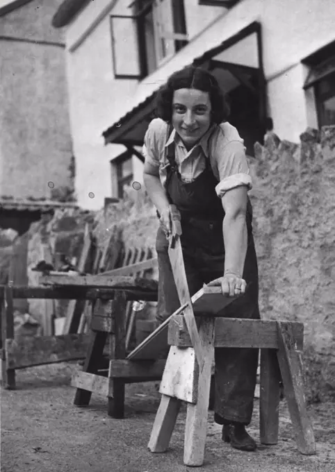 "The Right-Hand Woman" - Mrs. Farmaner sawing out wood as a carpenter. Mrs. Farmaner aged 28, two years ago was evacuated with her two children to Idford near Newton Abbot. She found time hanging on her hands, so tried her hand at gardening, with very pleasing results. She then told the local builder that she would like to help with building and repairs to country property; he gave her a trial, and she is now the right hand woman, of Mr. G. Hamilton to the village builder at Idford. September 2, 1942. (Photo by London News Agency Photos Ltd.).