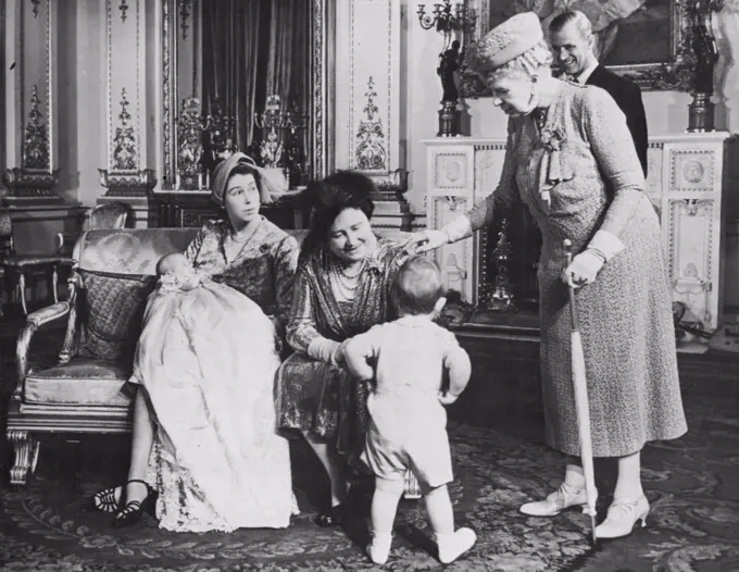 The Little Prince Who Wouldn't Join Royal Group - Queen Elizabeth and Queen Mary, right, try to talk the little Prince into turning round and face the cameras, while the Duke of Edinburgh seems to be enjoying the Prince's boyish pranks. His mother, Princess Elizabeth (holding Princess Anne) tends to make a sterner view.Prince Charles, now nearly two, already has a will of his own. When the Royal Family assembled in the blue drawing room of Buckingham Palace, London, for photographs to be taken following the christening of his little sister, Princess Anne, the Prince just refused to pose. After he had been persuaded to joint the Royal group he scampered away again, slid on the polished floor and took refuge behind a settee. October 23, 1950. (Photo by Paul Popper Ltd.).