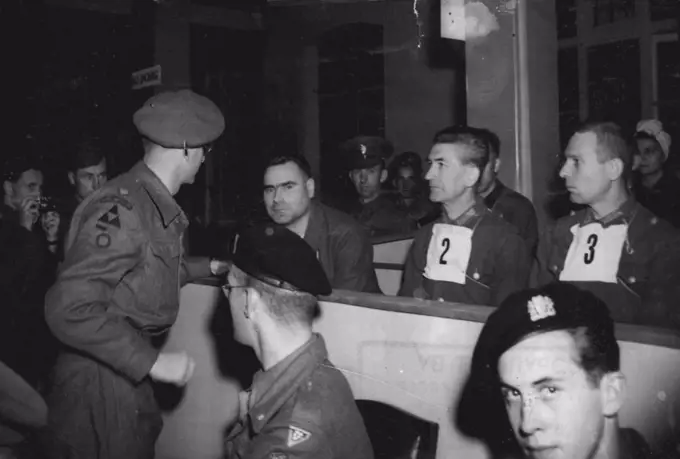 Kramer's defence council, Major T.C.M. Winwood, of reading, who was a London sclicitor before joining the army, speaks to the beast of Belsen, during the first days trial at Luneberg.The first of the war criminal trials to be held in Germany, began on September 17 at Luneburg, when Josef Kramer, "The Beast of Belsen" took his stand in the specially prepared courtroom at Lunenburg, together with 29 men and 19 women who will also be charged with the ill-treatment of allied war prisoners. October 15, 1945. (Photo by Associated Press Photo)